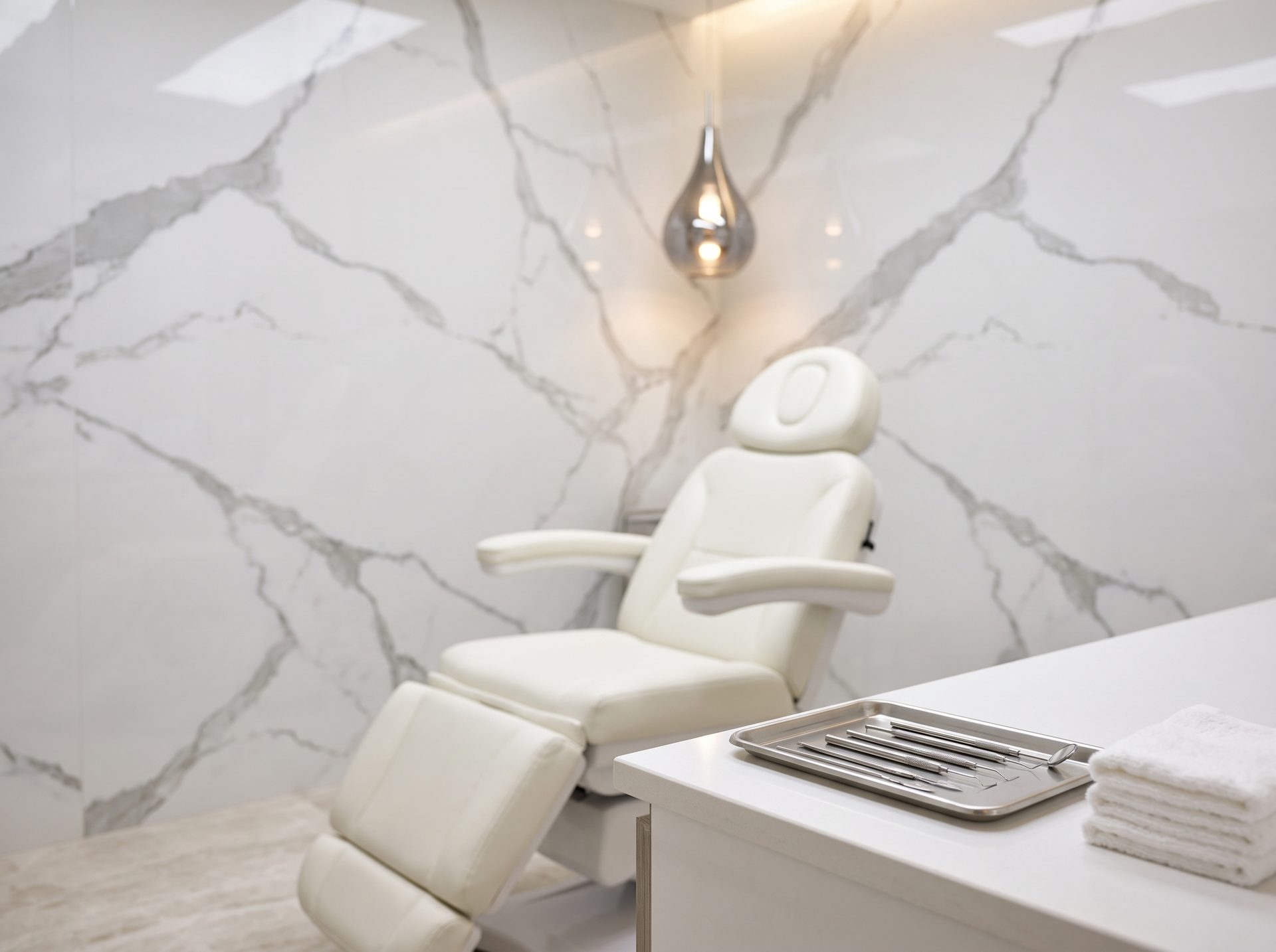 Behandelkamer met crèmekleurige behandelstoel en marmeren wand